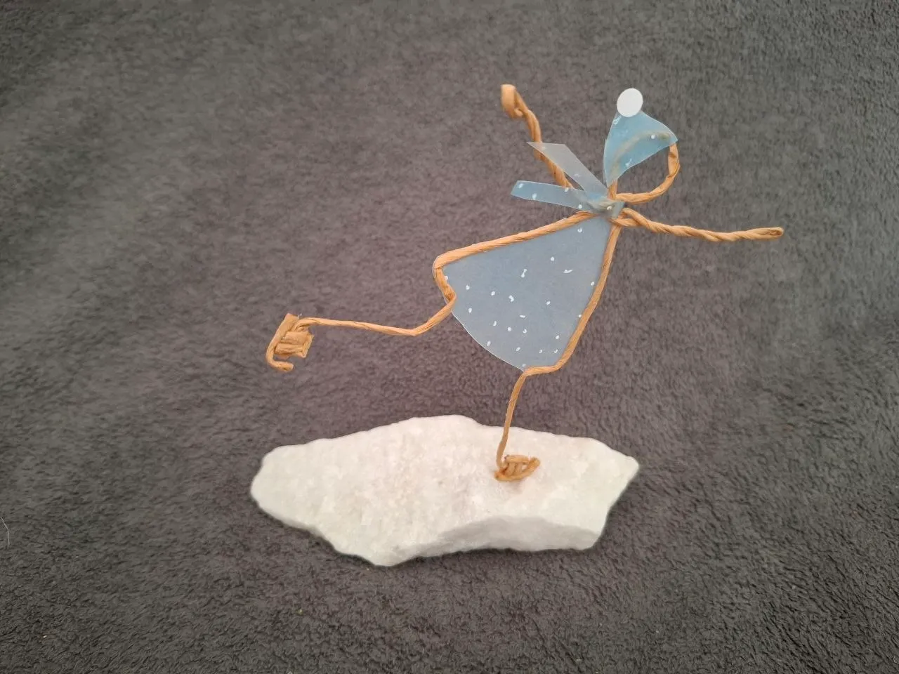 Ein auf dem Eis tanzende Papierdraht-Figur mit Schal und Sternchen-Muster auf dem Kleid